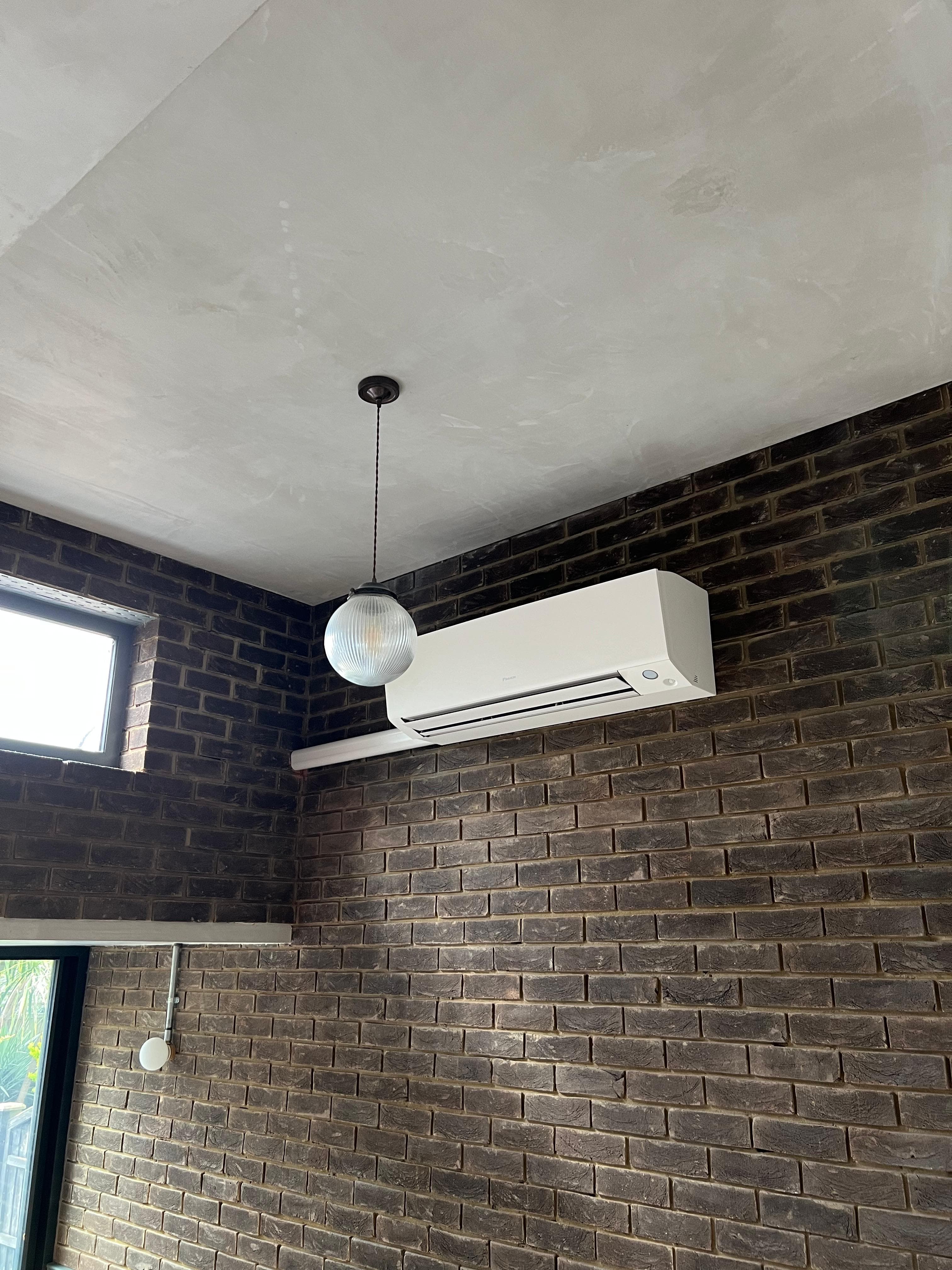 Daikin Perfera unit mounted against an exposed brick wall