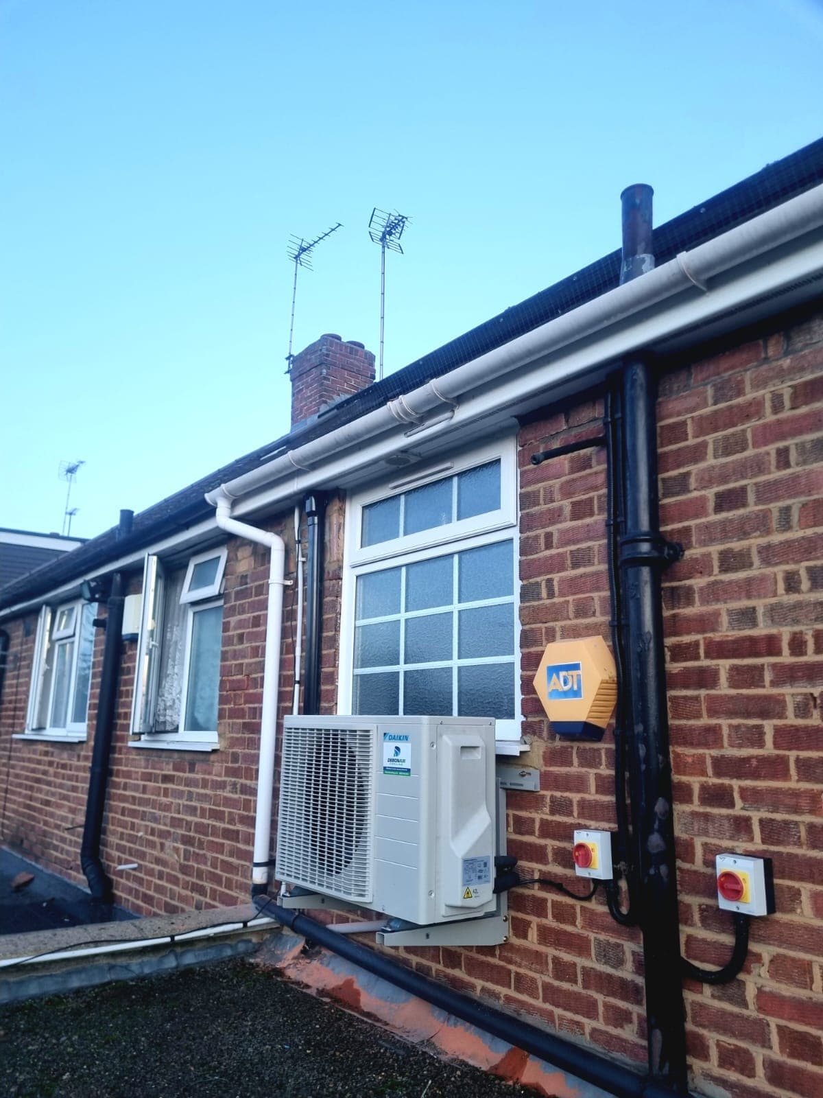 Outdoor condenser unit mounted on a brick wall bracket