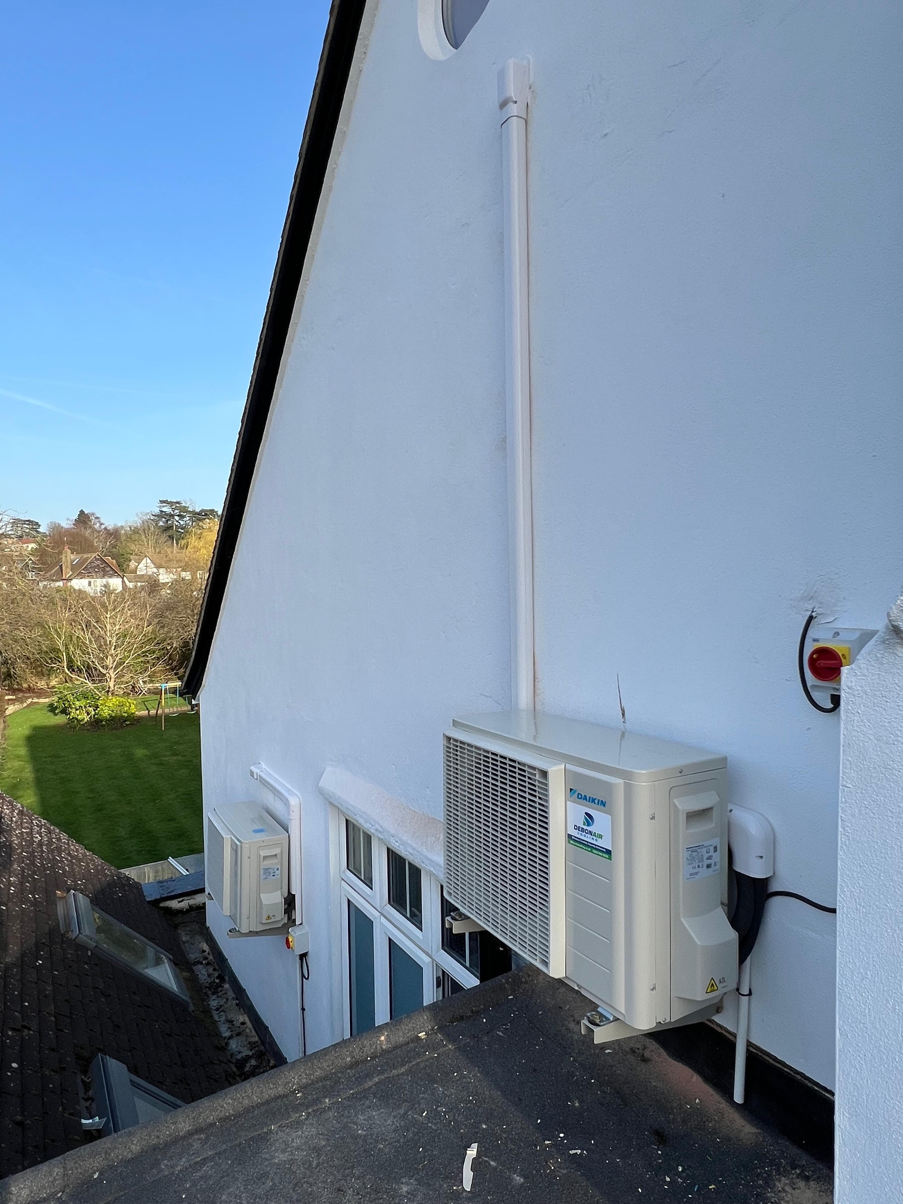 Second condenser bracket on white rendered wall - neat finish