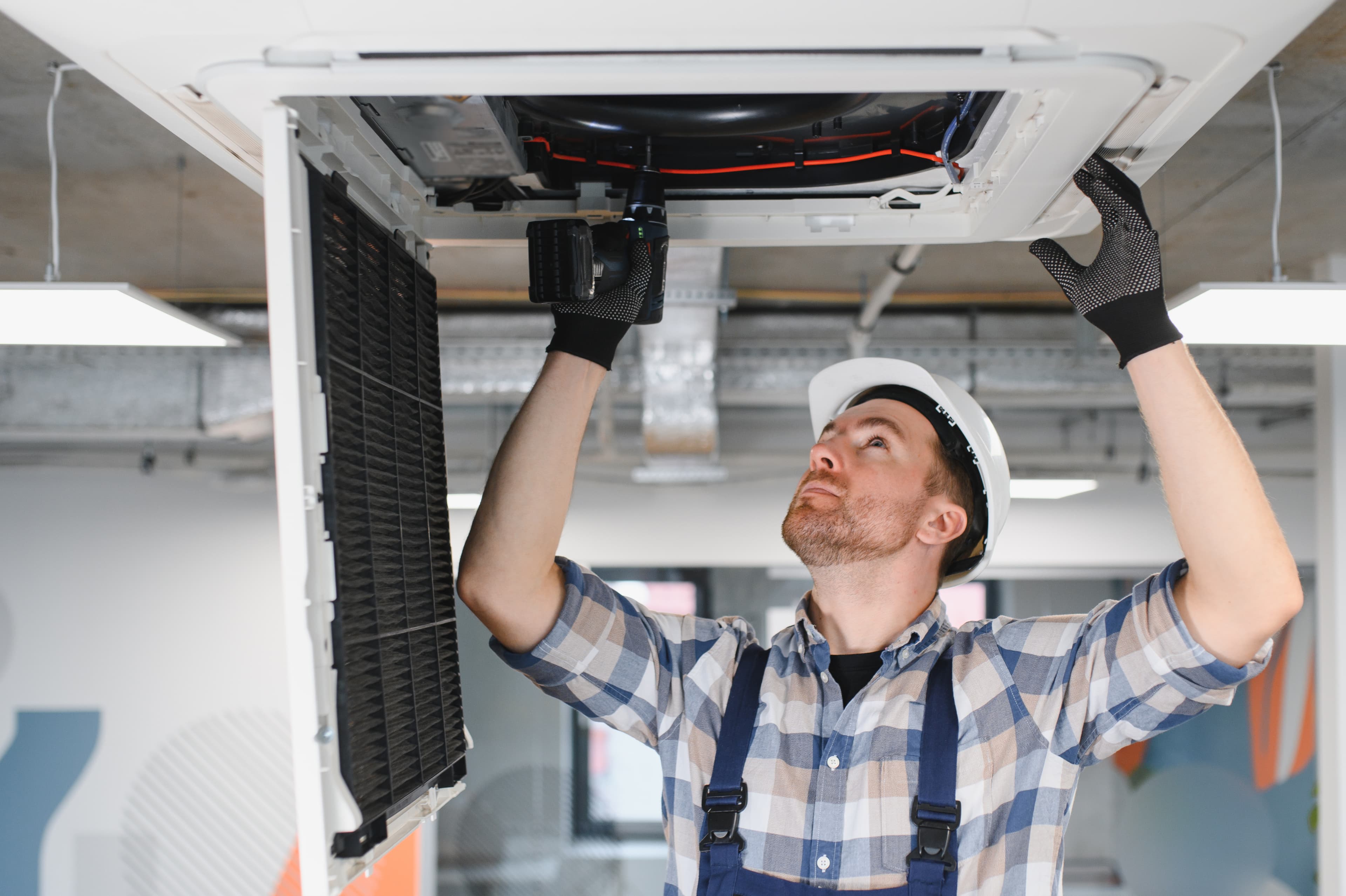 Engineer installing a ceiling-mounted air conditioning indoor unit