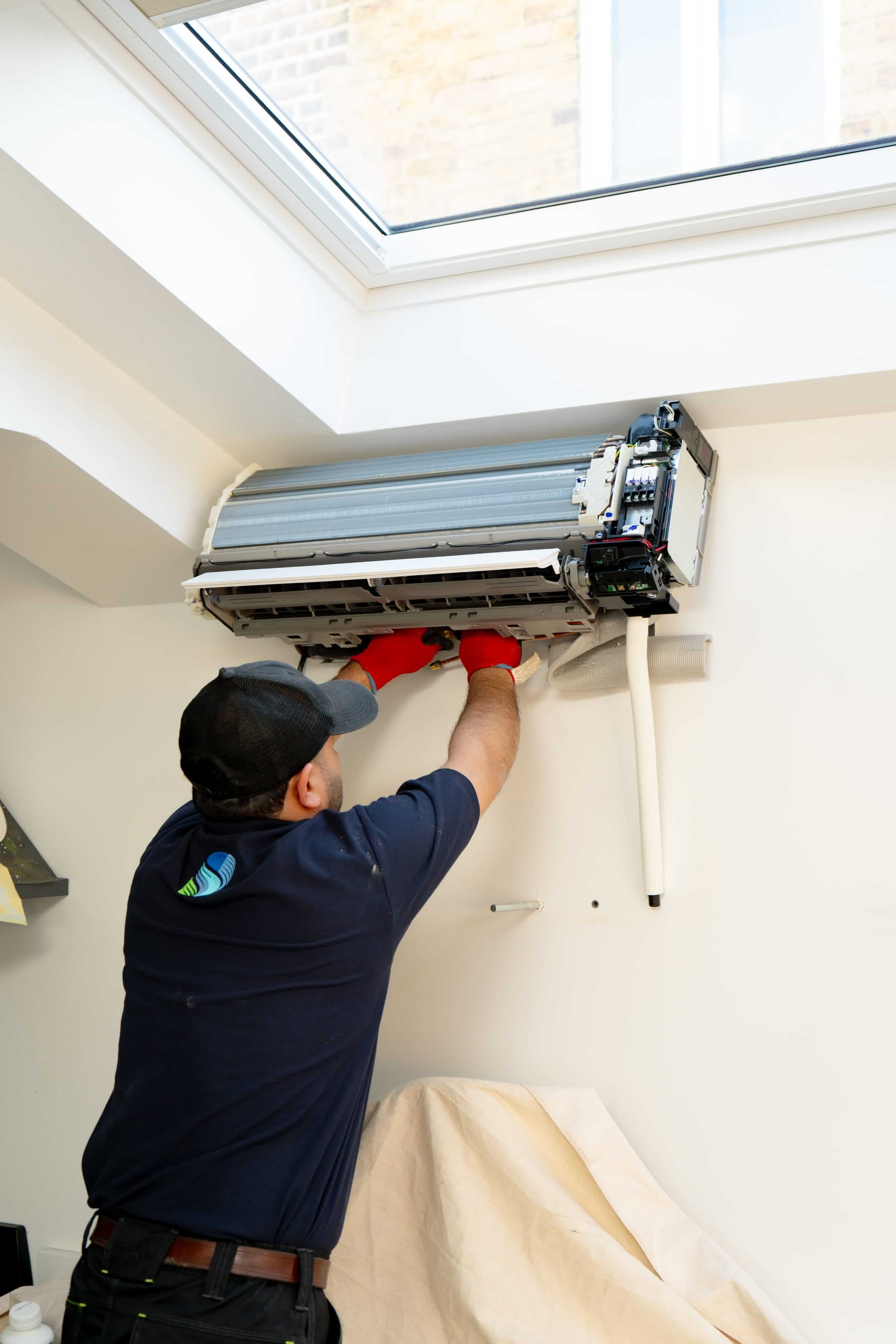 AC engineer servicing a wall-mounted air conditioning unit