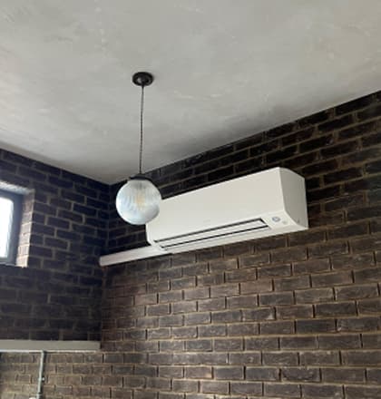 Slim white air conditioning unit under a skylight in a modern space